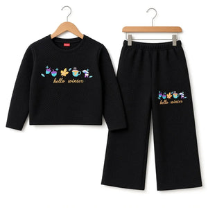 A two-piece children's outfit set consisting of a black textured long-sleeve top and matching black cropped pants, both hanging on wooden hangers against a white background. The top and pants feature a colorful graphic of winter-themed characters (snowman, carrot, snowman, snowman, snowman, snowman) above the gold text 'hello winter'.